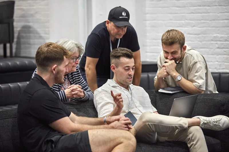 Five people sitting around a laptop