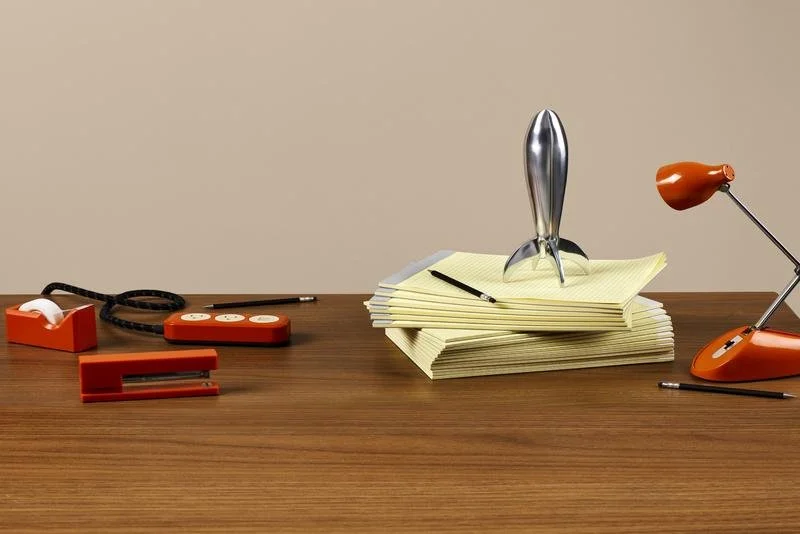 A silver rocket ship on a stack of yellow legal pads