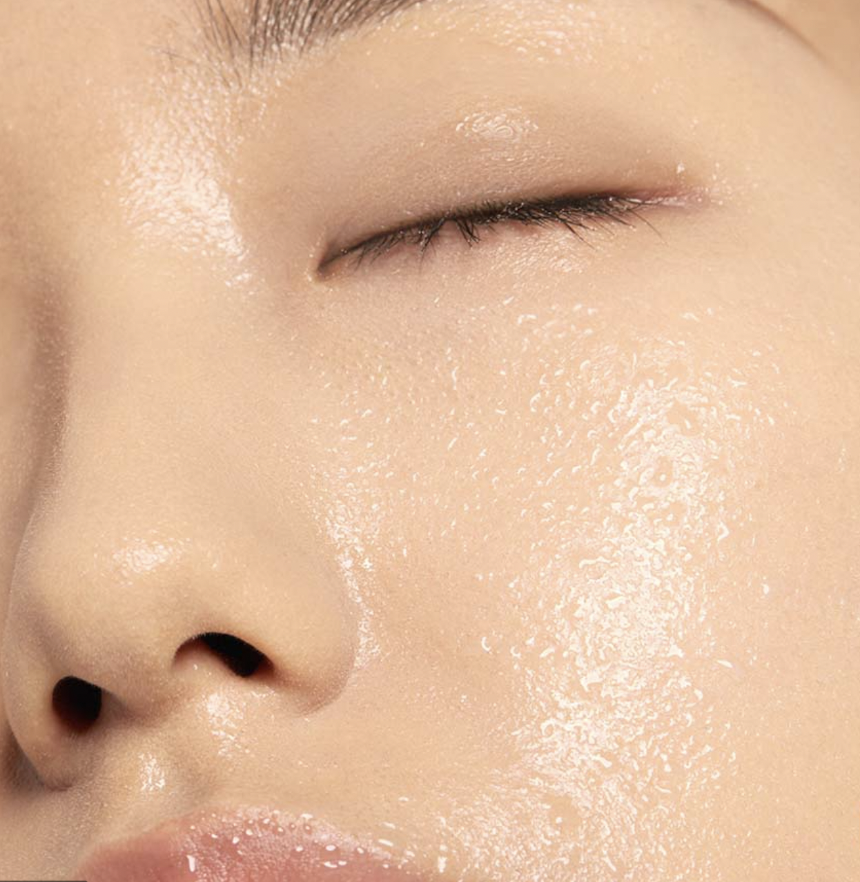 Close-up of a person's face with wet, dewy skin and closed eye.
