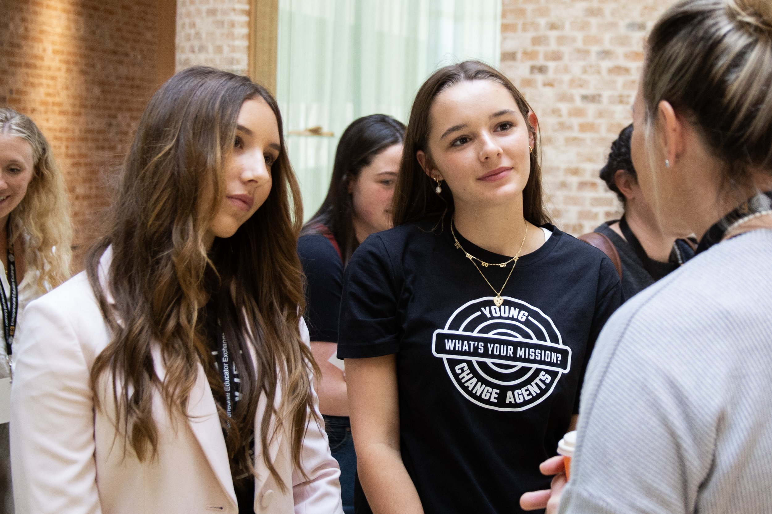 Group of young women engaging in conversation during an indoor event.