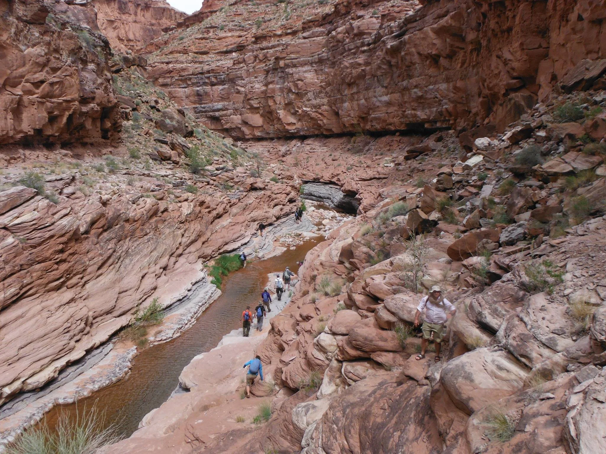 Group hiking through red rock side canyon along the Colorado River in Canyonlands National Park.