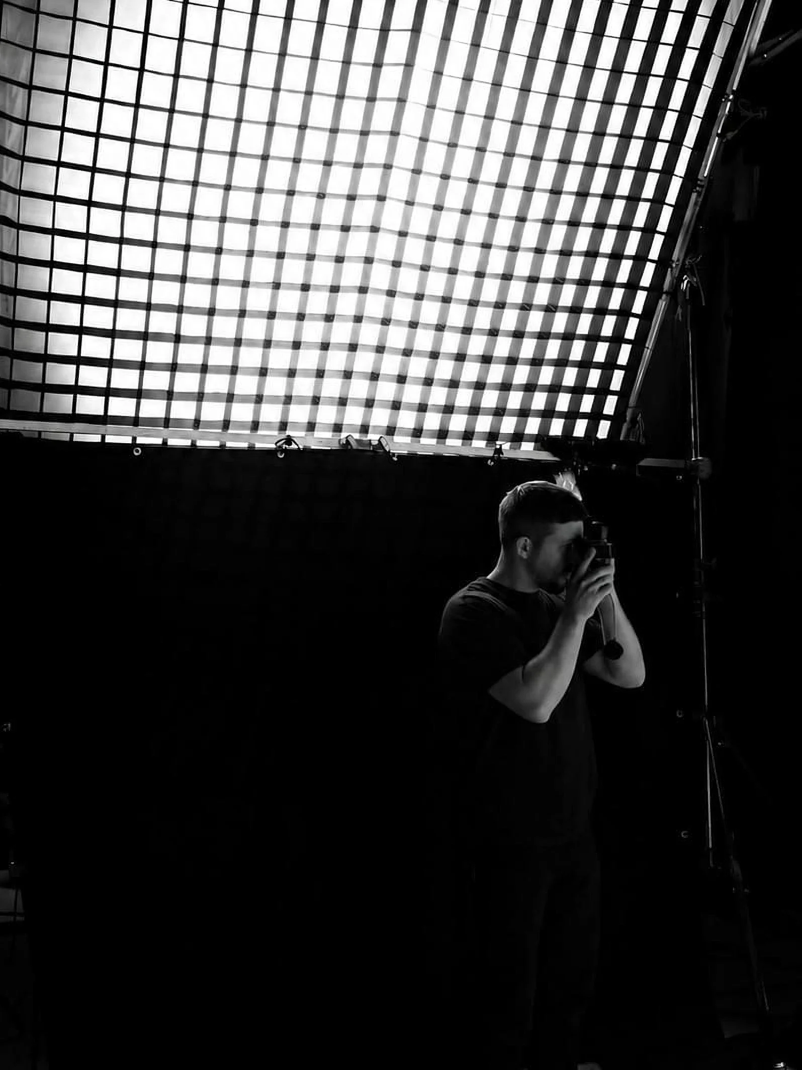 A man taking a light measure with a light meter, in black and white.