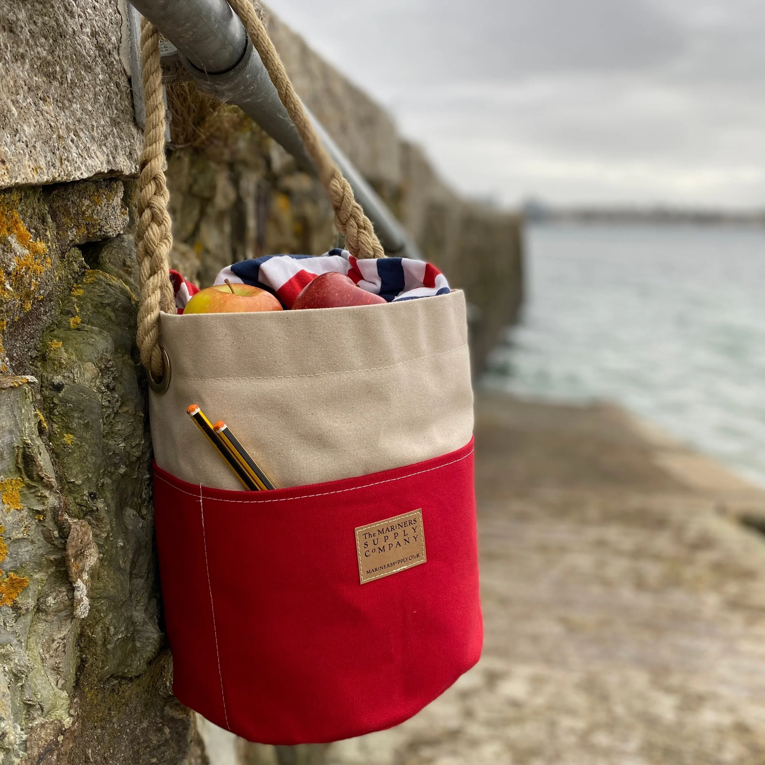 Nautical ditty bag in red and cream traditional canvas with rope handle.