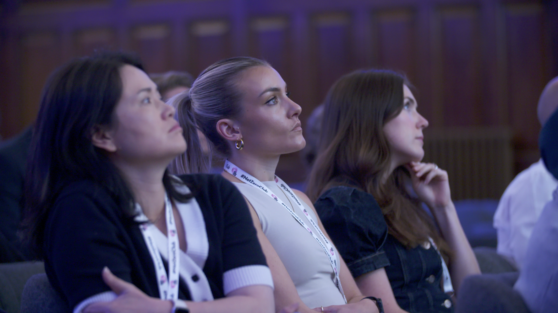 Three women attending a conference, sitting attentively and listening.