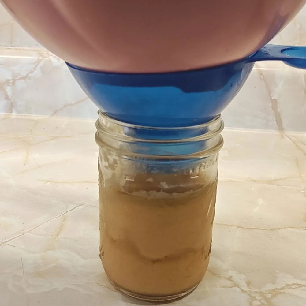 A canning funnel and mason jar make it easy to harvest paw paws for storage.