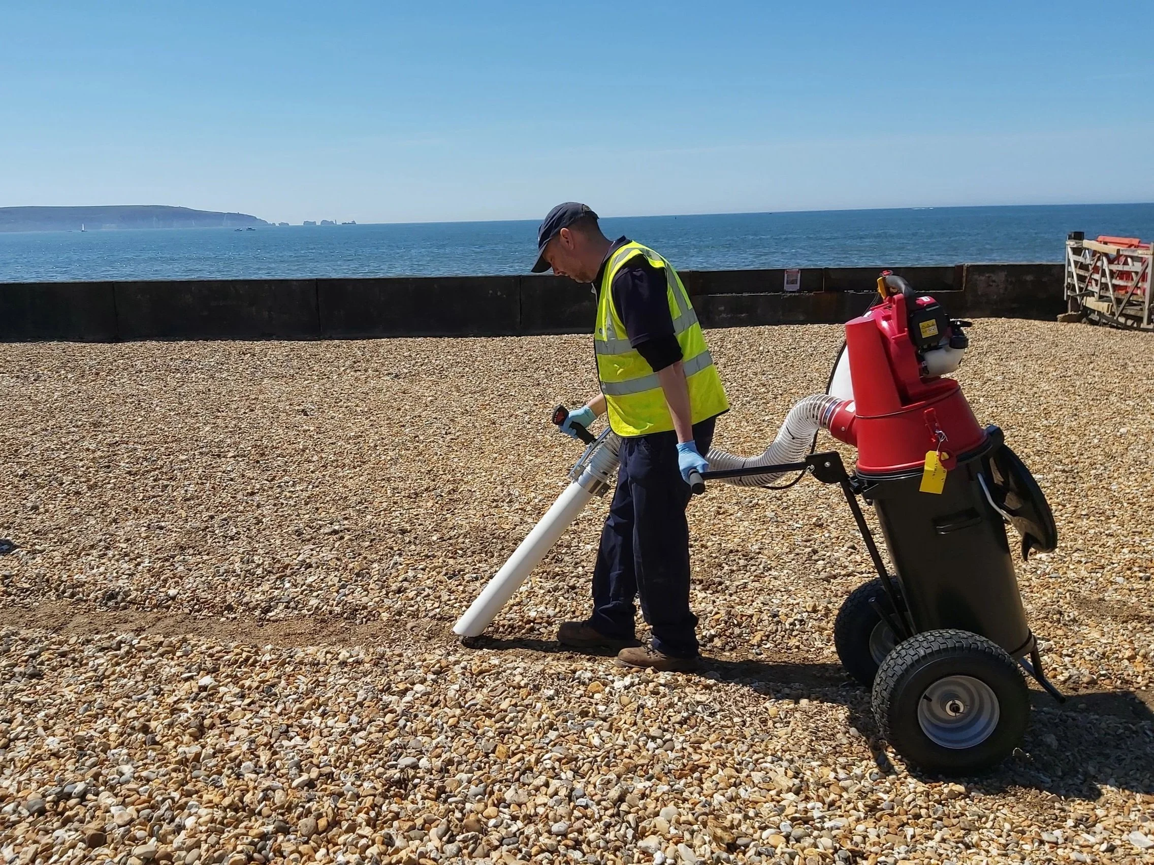 Photo of a staff member using a modified vacuum system on a beach.