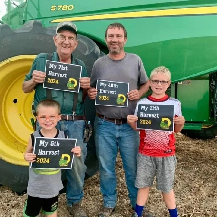  Drost family holding signs indicating how long they’ve been farming. 