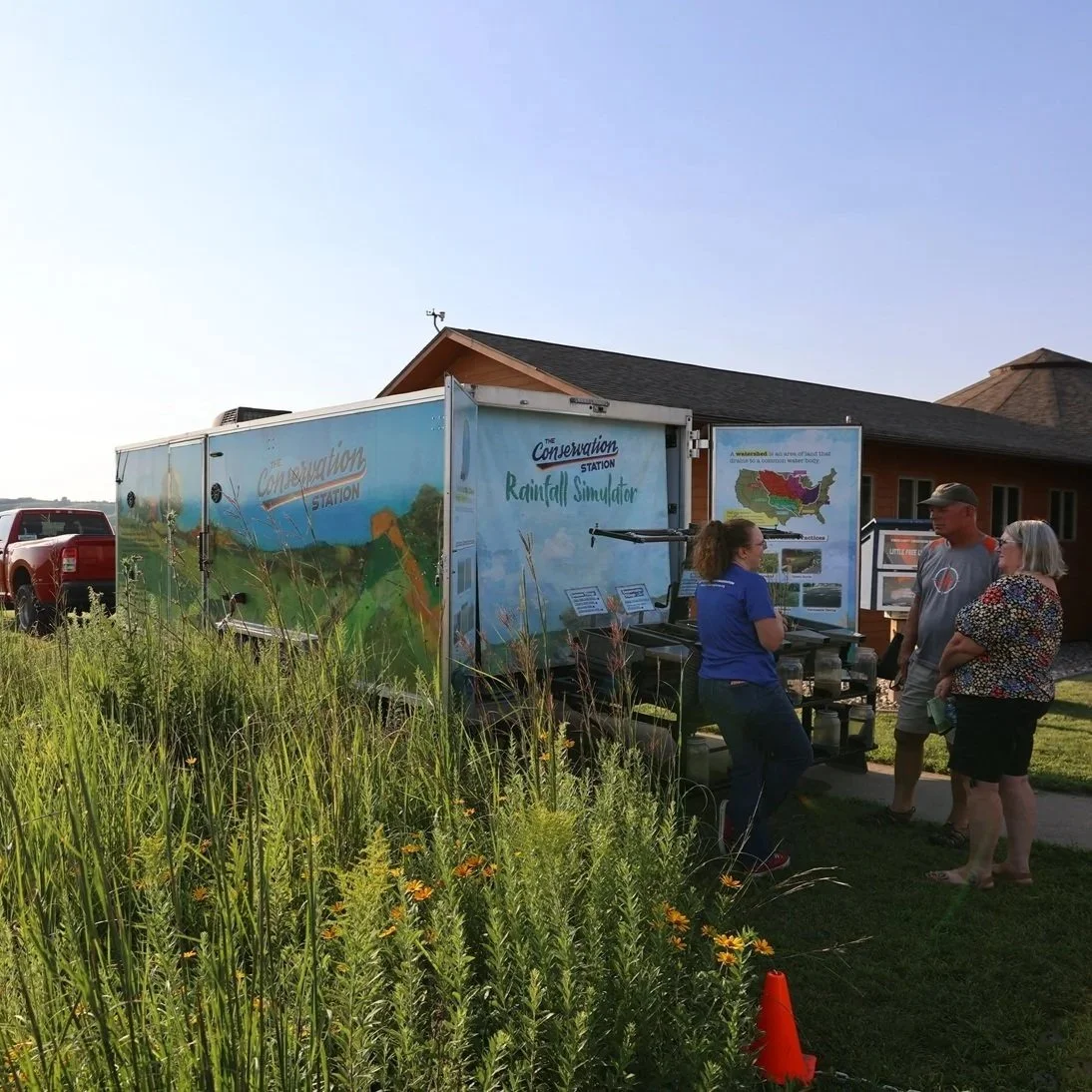  Three people engaging in dialogue at the Conservation Station trailer 
