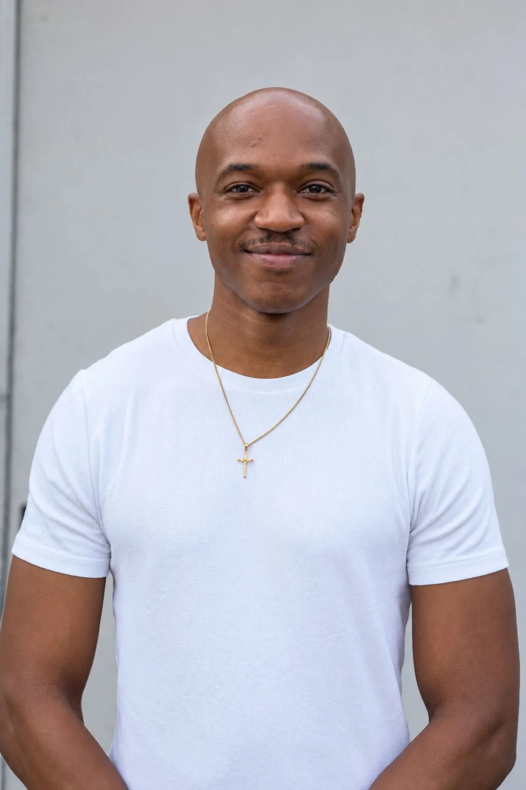 Caleb Jones smiling and wearing a brown sweatshirt standing against a white background.