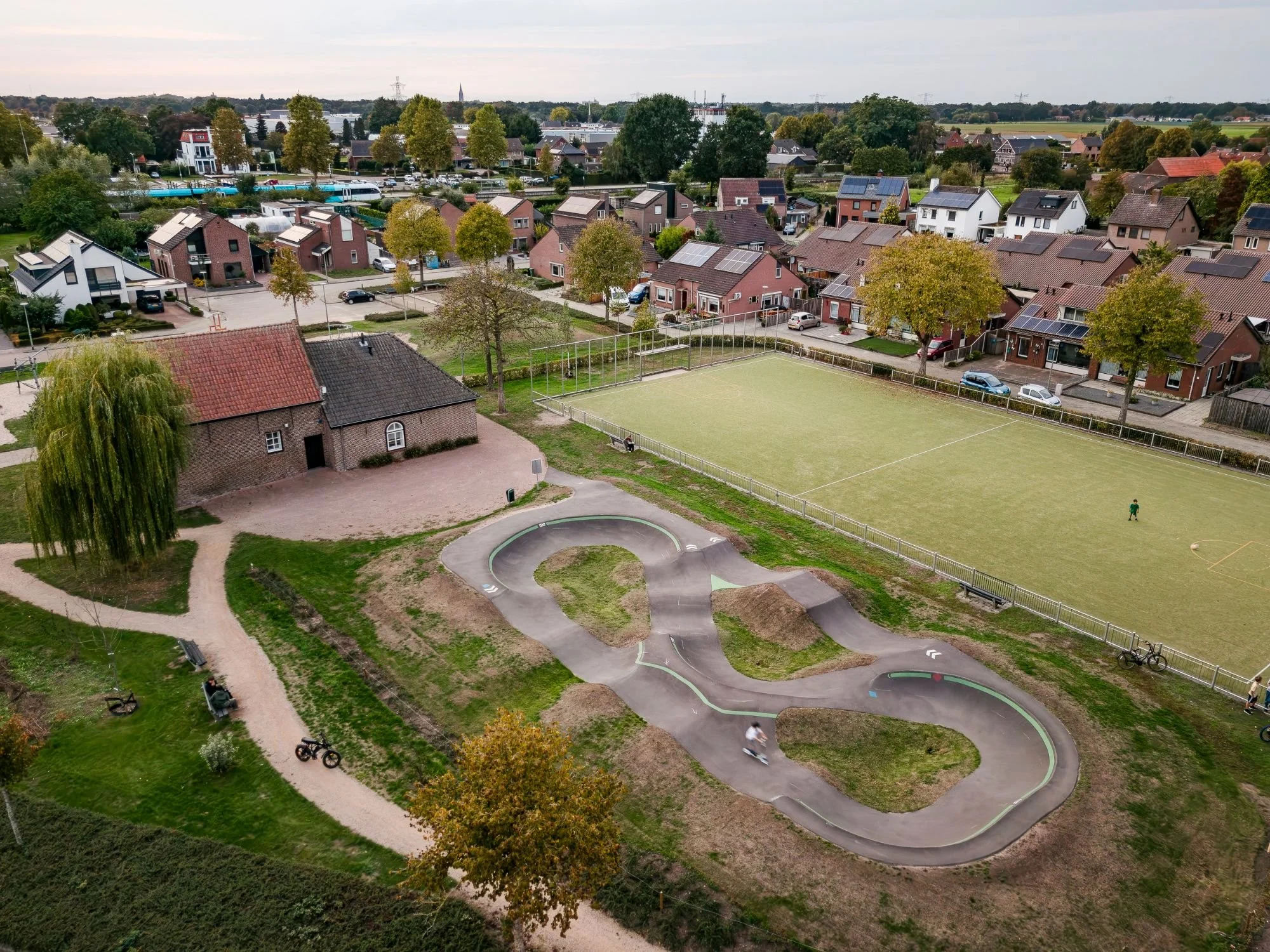 Pumptrack Oostrum tussen woningen en sportvelden, luchtfoto