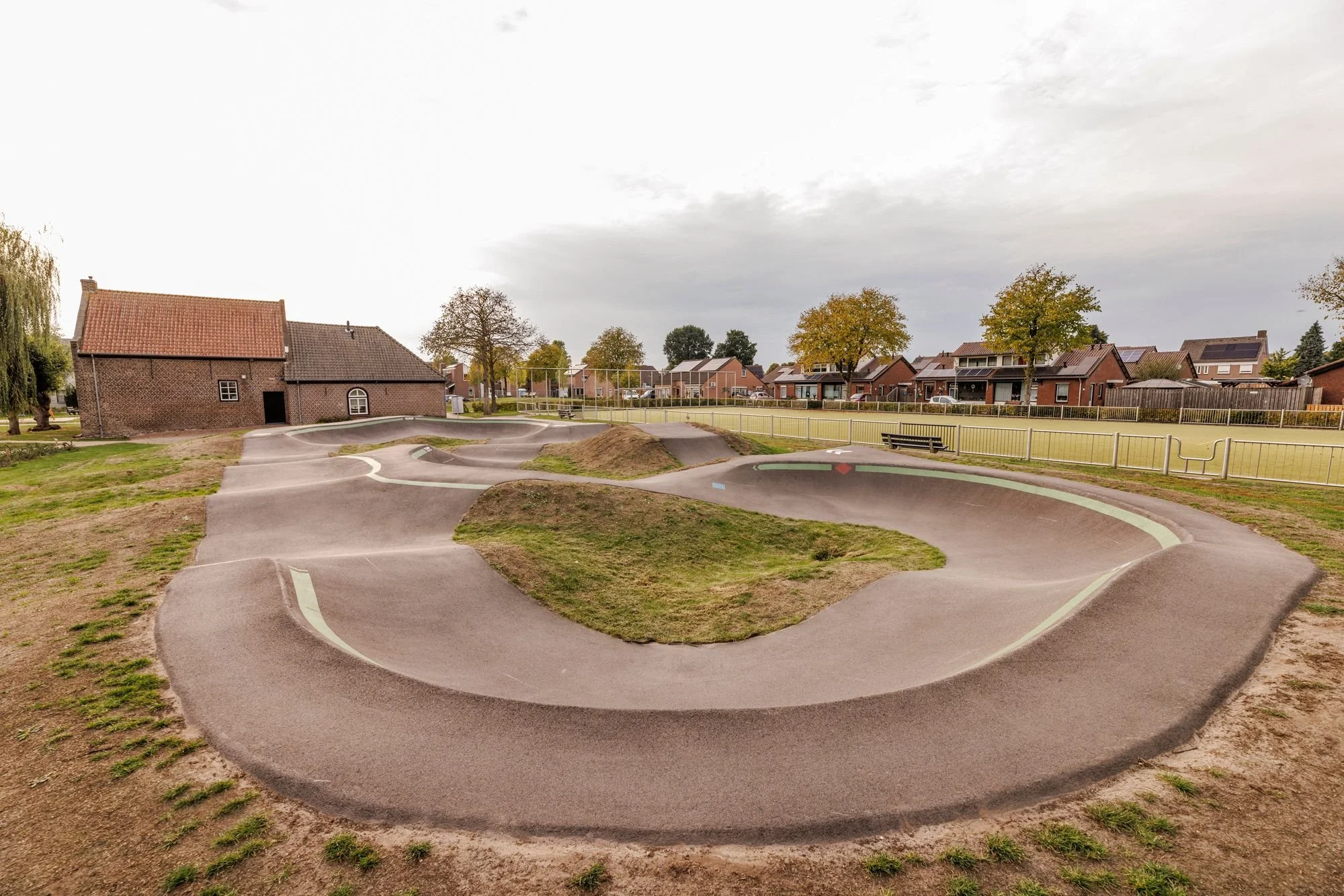 Bocht van pumptrack Oostrum met boerderij op de achtergrond