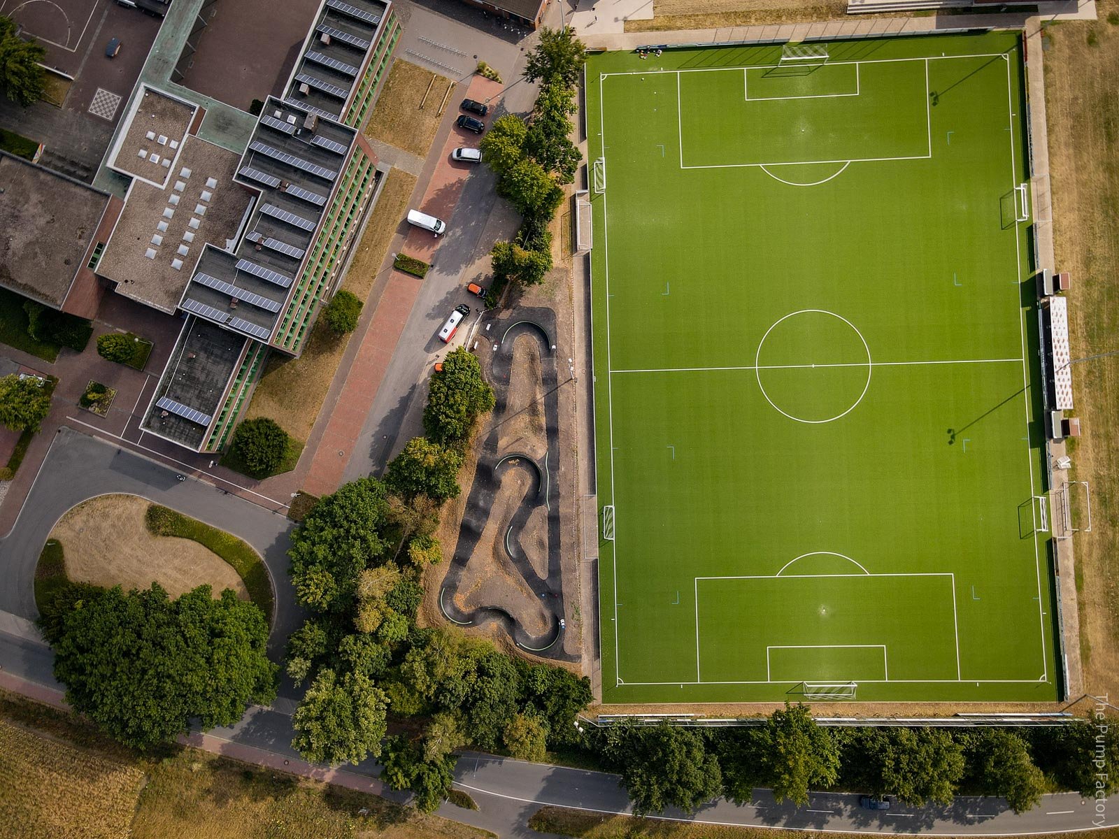 Lucht foto van Pumptrack in Duitsland naast voetbalveld en schoolgebouw.jpg