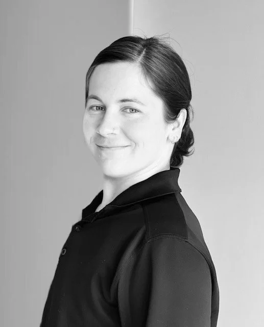 Black and white portrait of a woman with dark hair pulled back, smiling softly, wearing a dark collared shirt.