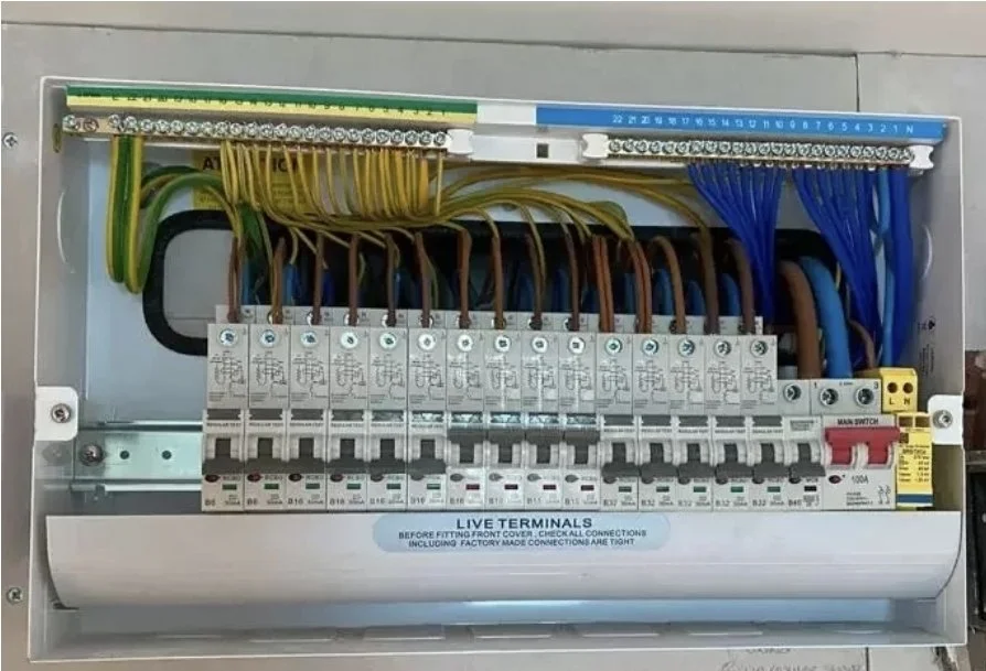 Electrical control panel with colorful wiring, circuit breakers, and live terminal connections.