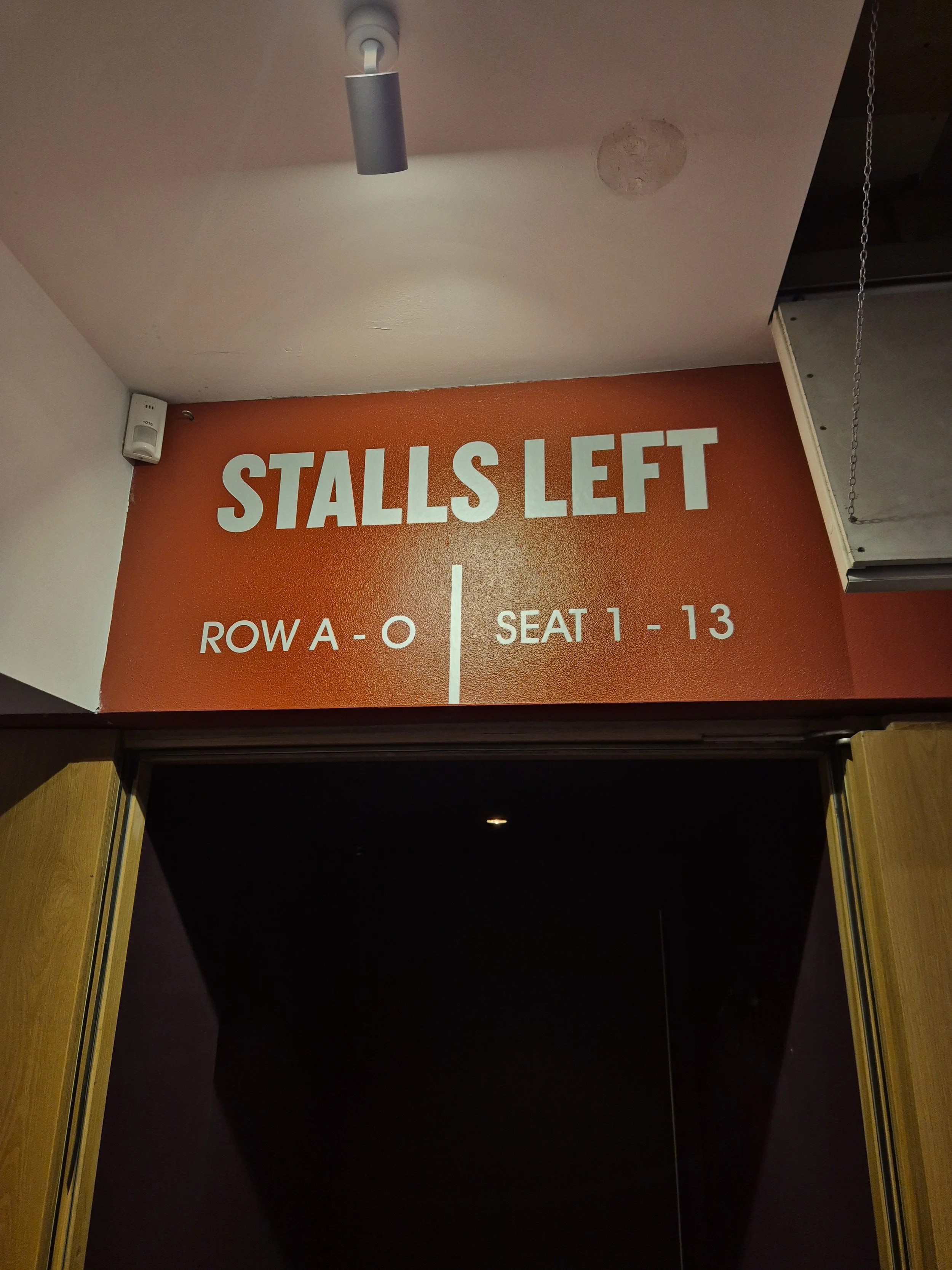 Sign indicating that stalls are left, with rows labeled A to O and seats 1 to 13.