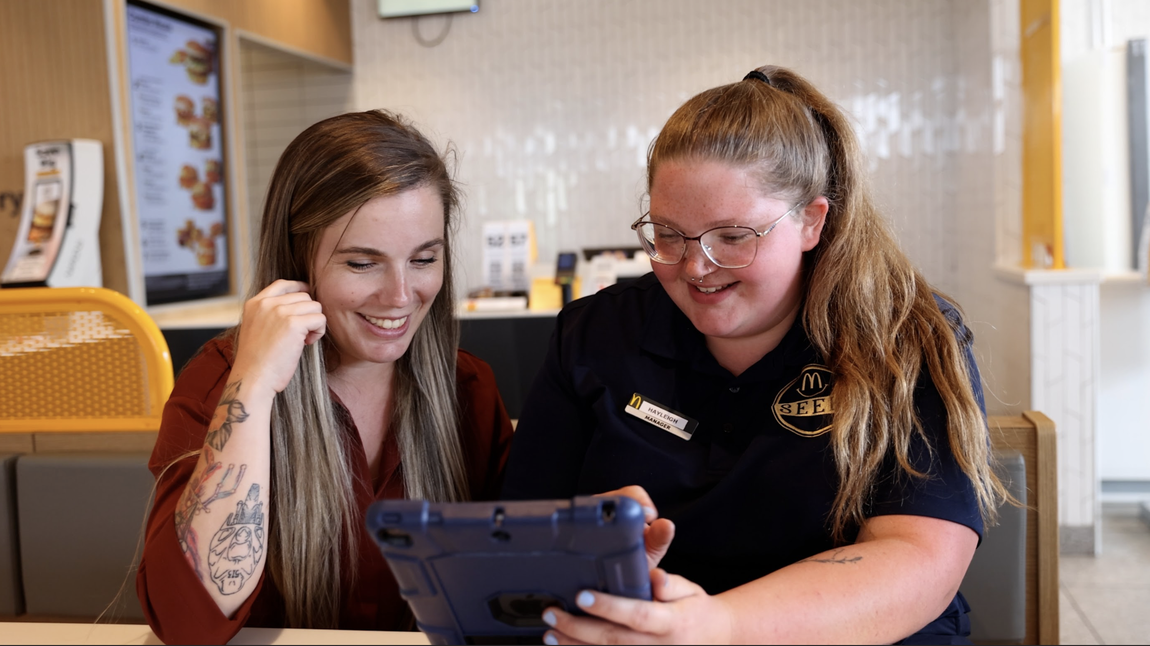A McDonald's employee showing a customer something on a tablet in the restaurant.