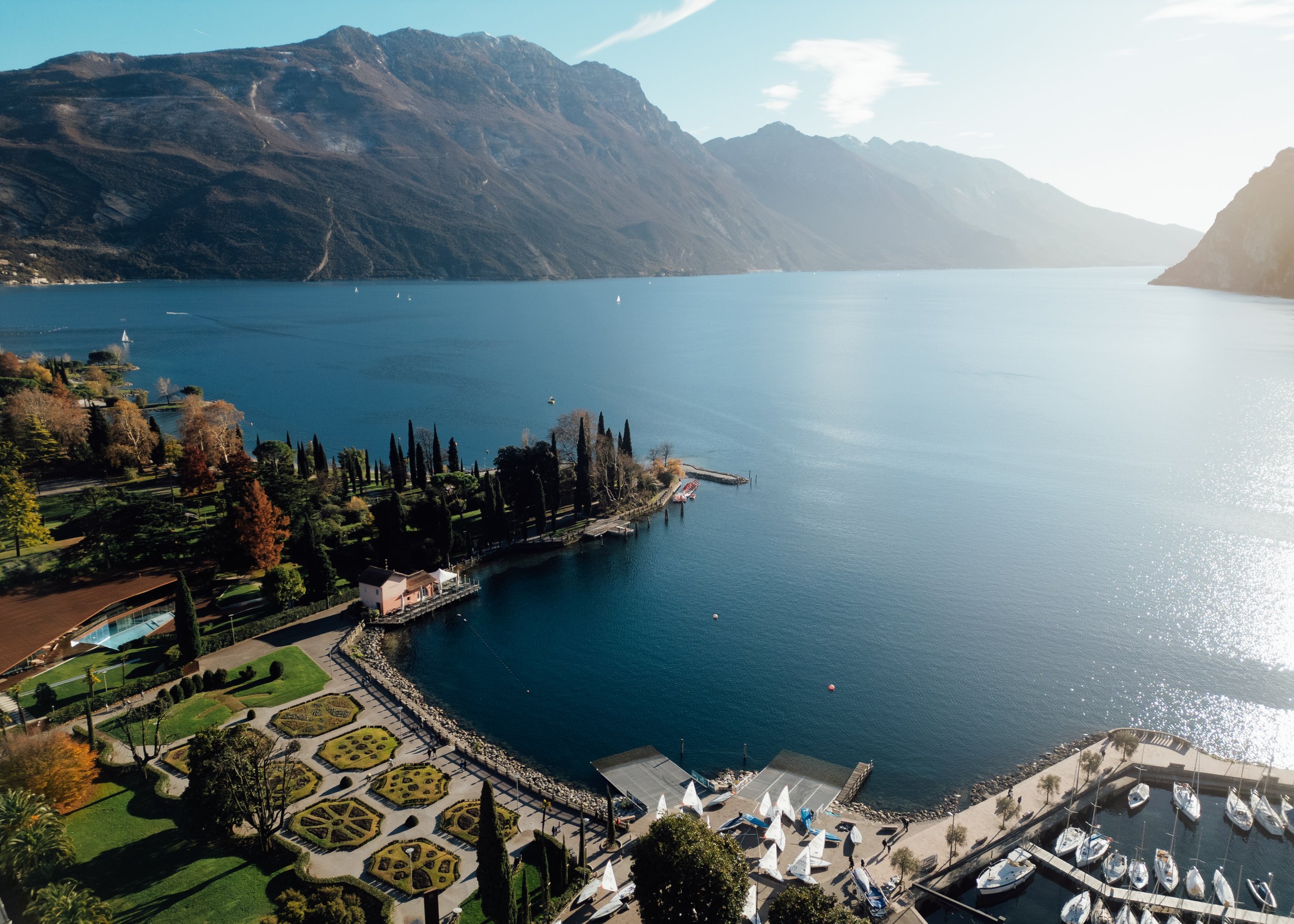 Aerial wide shot of North Lake Garda with steep mountains, blue waters, and lakefront gardens