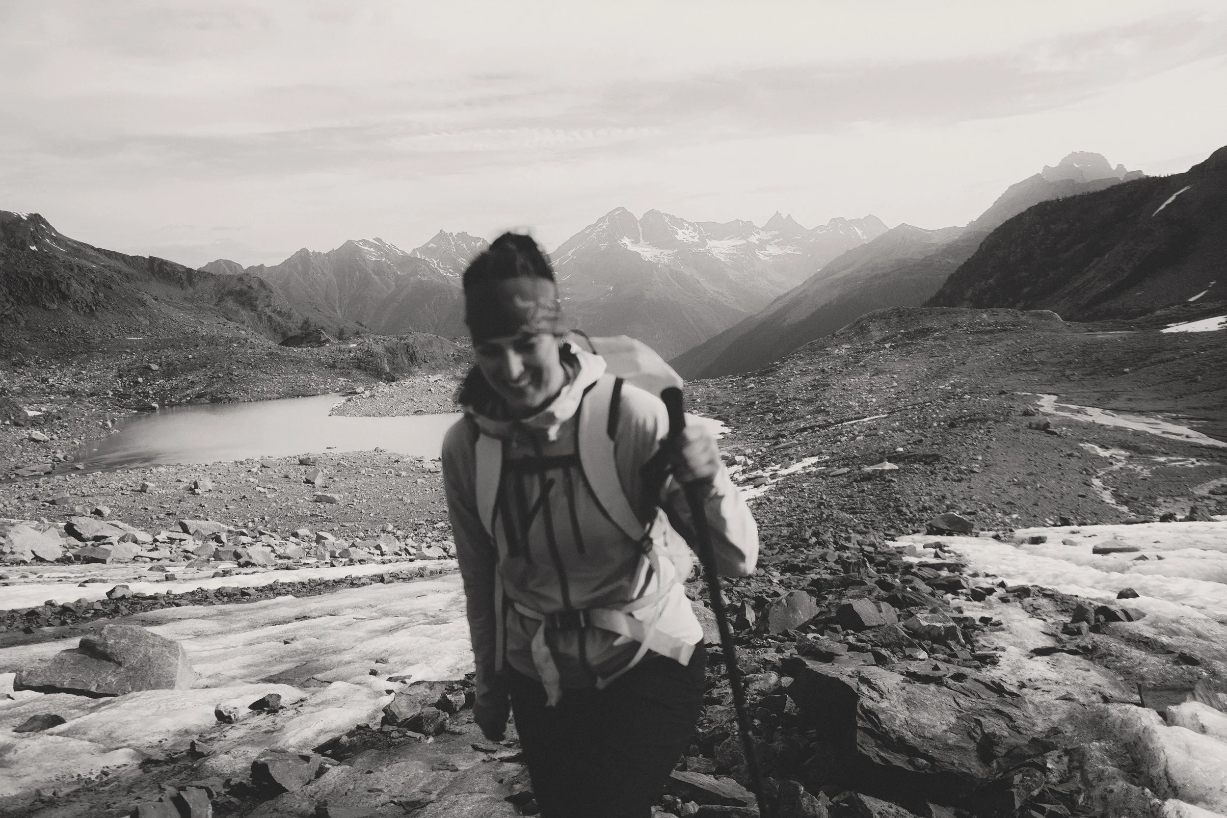 Alex Mack hiking through rocky alpine terrain with mountain range in the background, Hatteras 2025, Purcell Mountains, British Columbia