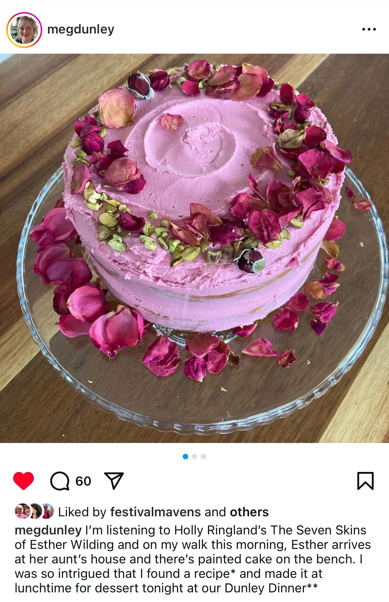 Pink rose-flavored cake topped with dried rose petals, on a glass cake stand.