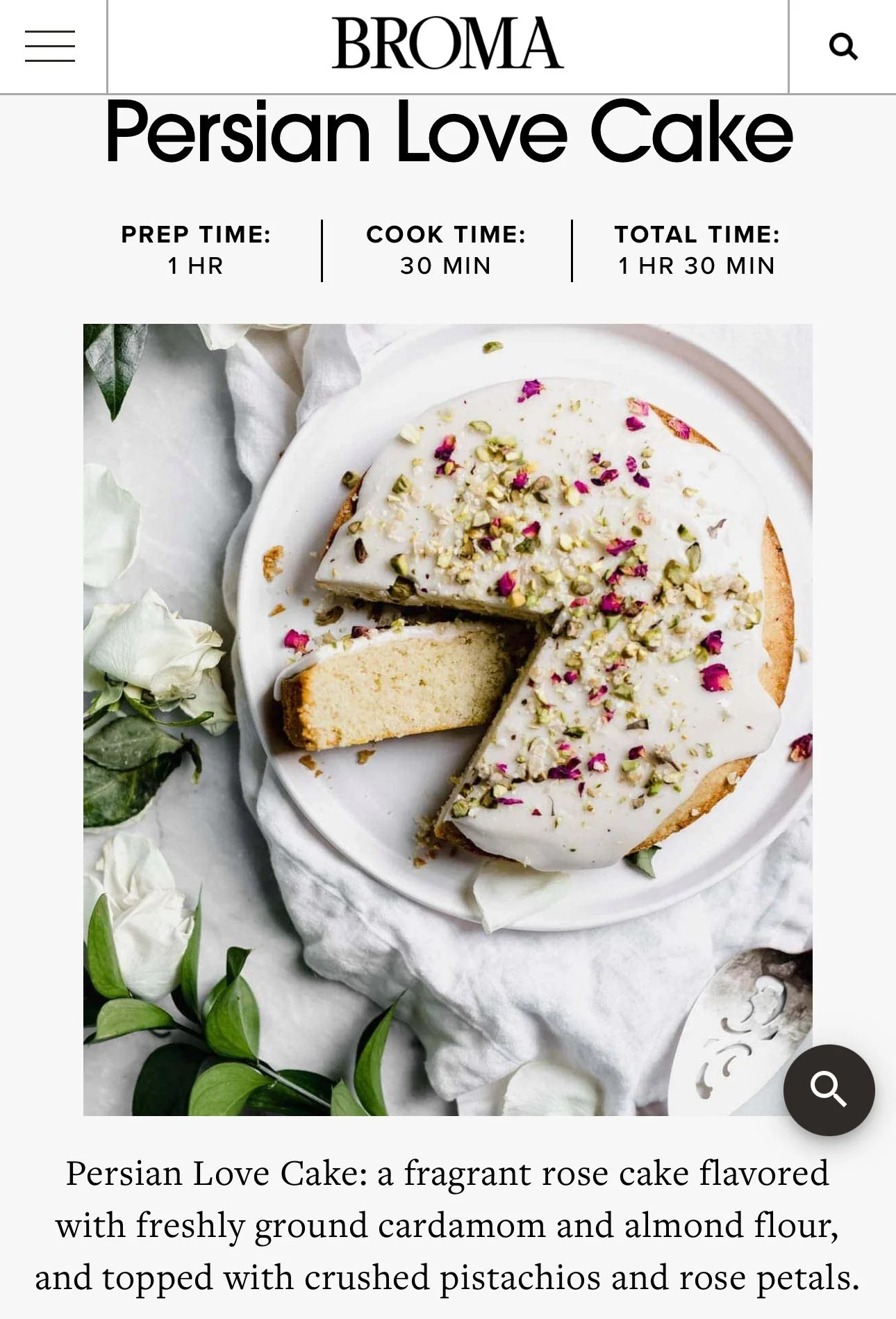 A white rosewater-flavored cake topped with crushed pistachios and rose petals, with one slice cut and slightly pulled away, on a white plate surrounded by white roses and green leaves.