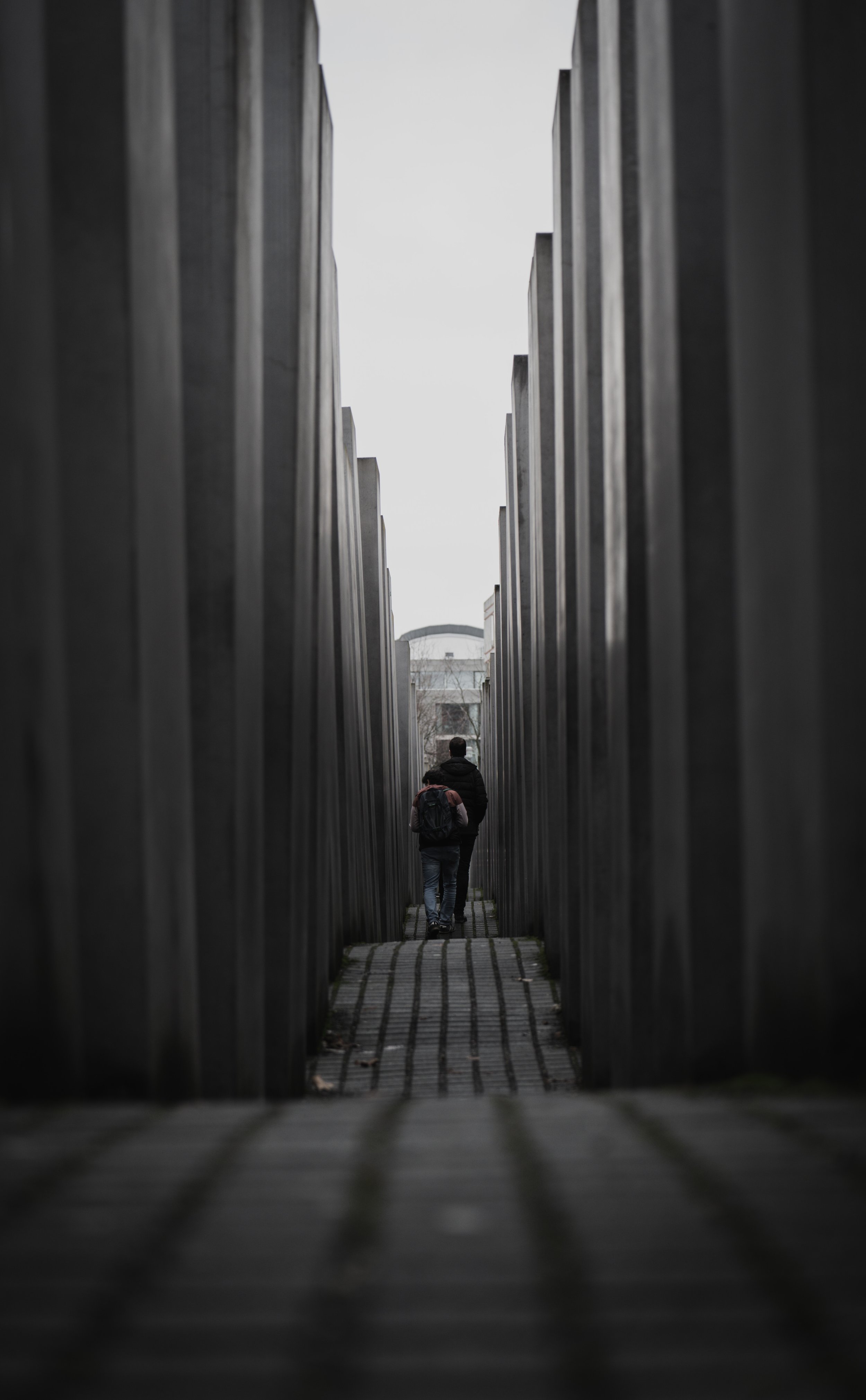 People walk inside the Memorial to the Murdered Jews of Europe in Berlin, Germany, on Jan. 3, 2022. The memorial consists of hundreds of irregular stone pillars placed in uneven rows. The rolling path keeps visitors constantly off balance, generating
