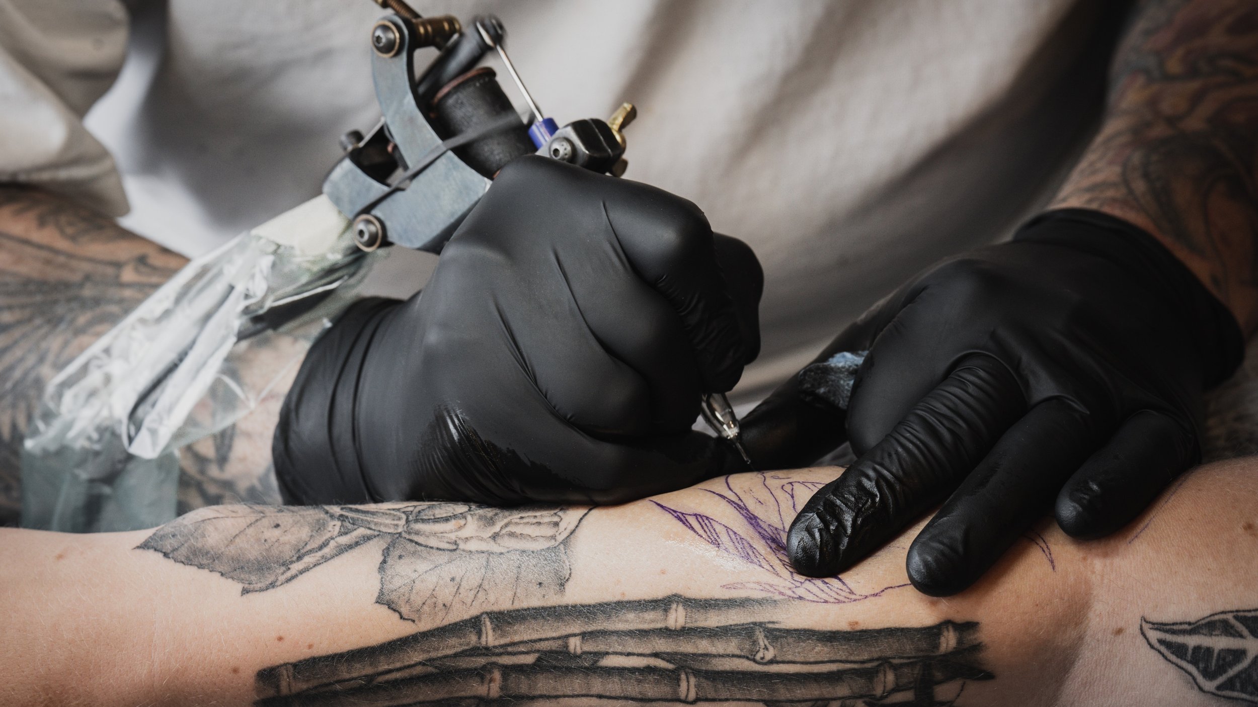 Dark Light tattoo artist Shiloh James tattoos a client on Apr. 23, 2022, in Fort Collins, Colo. Despite his intimidating lumberjack aura, James is always quick to crack jokes and make customers feel at ease. Photo by Merit Davey.