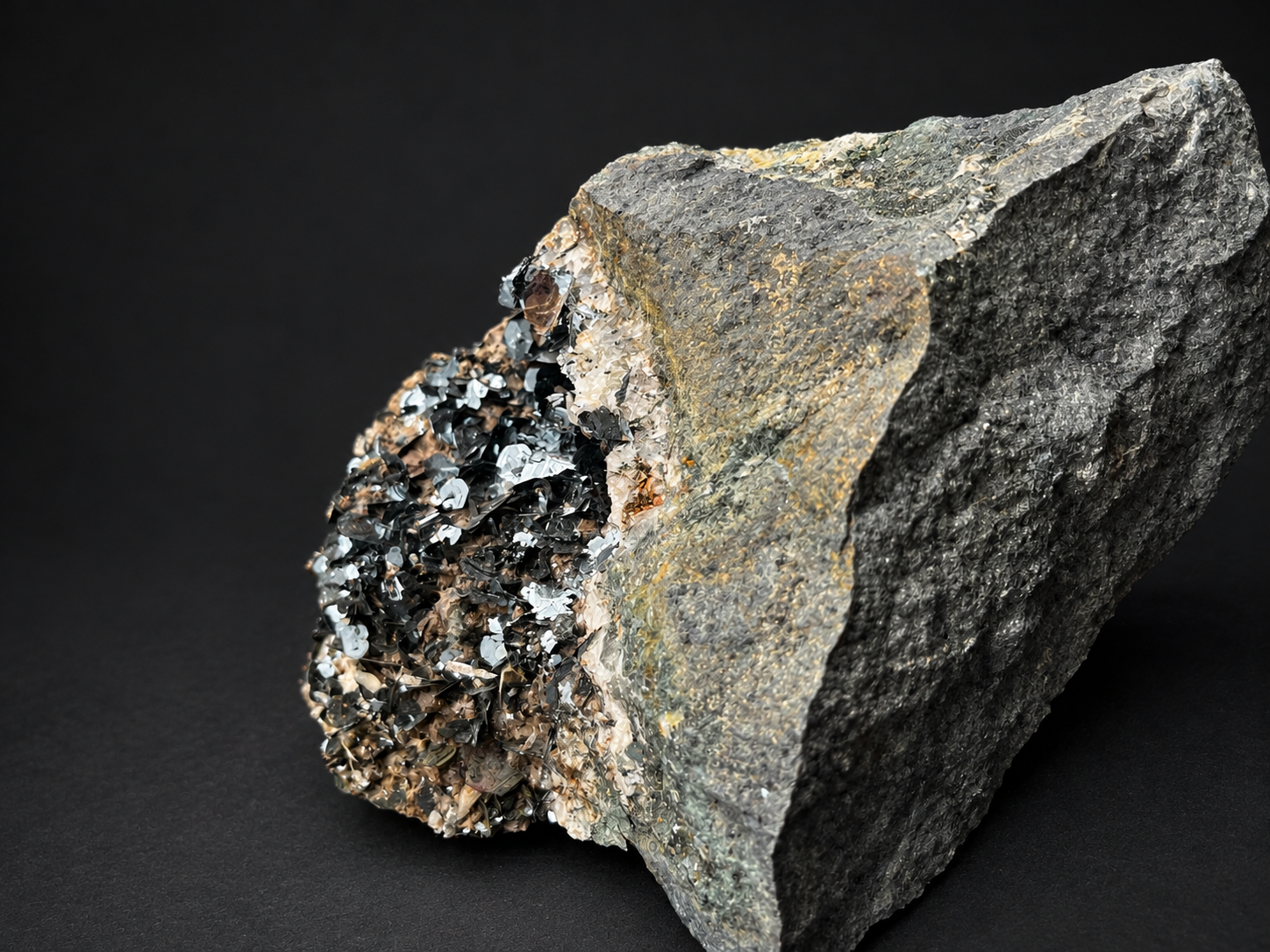 Large bladed hematite specimen from Nador, Morocco, featuring dense clusters of reflective black metallic crystals beside natural gray host rock.