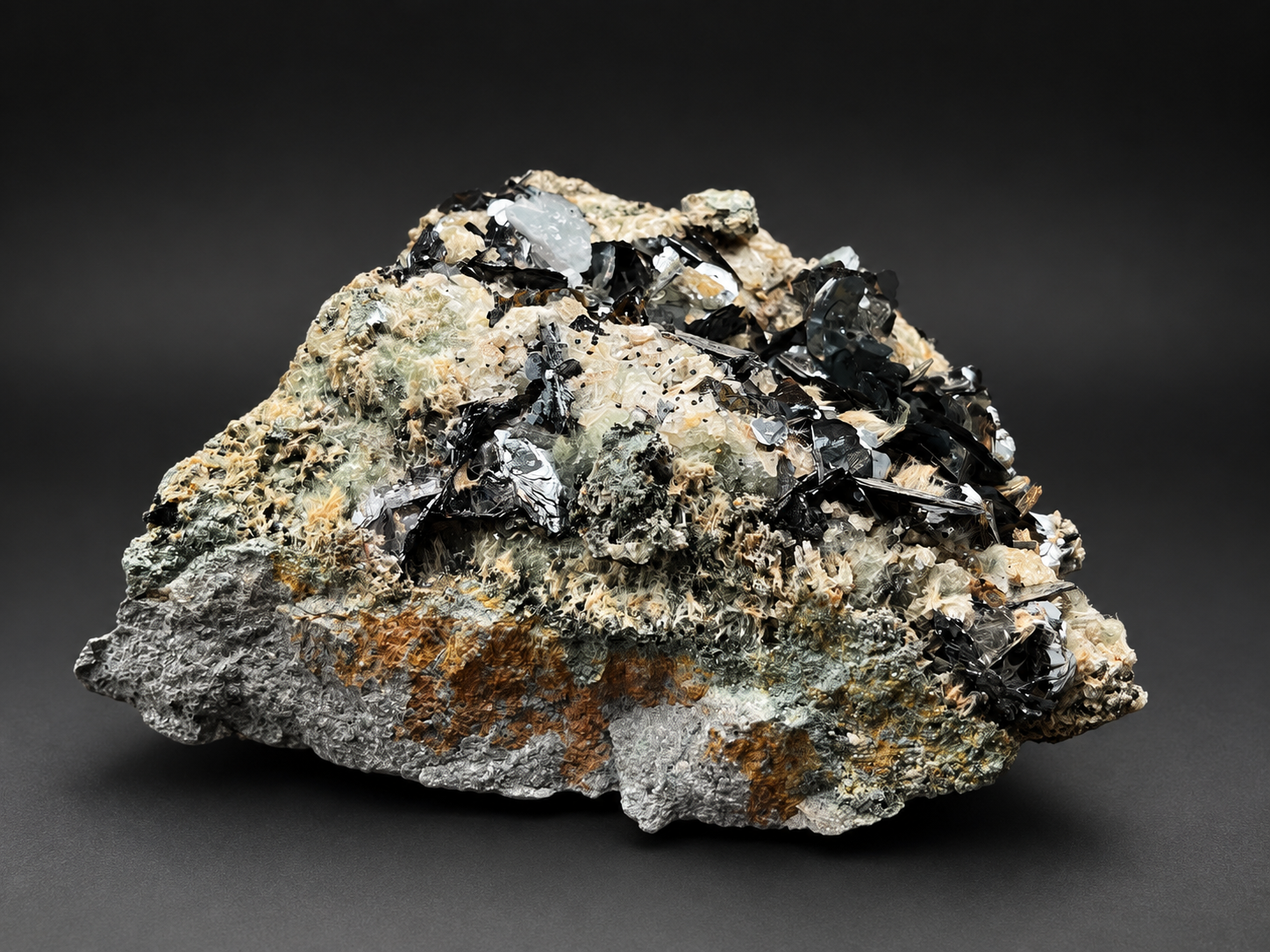 natural Nador hematite showing contrasting cream and gray rock with scattered reflective black crystal blades and silver metallic faces.