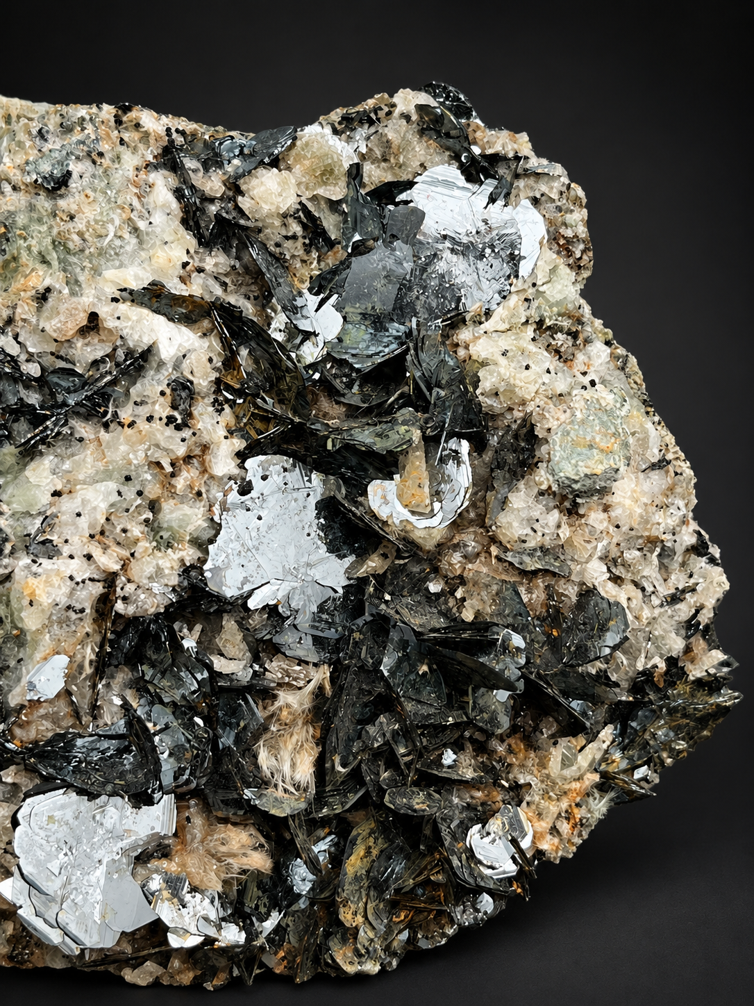 Nador specularite hematite showing thin overlapping black metallic blades and highly reflective silver crystal faces against cream-colored rock.