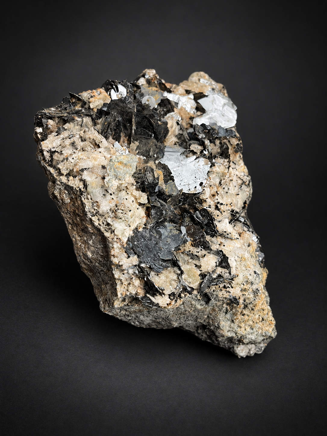 Moroccan bladed hematite featuring broad silver-gray crystal faces, overlapping dark metallic plates, and light-colored natural surroundings.