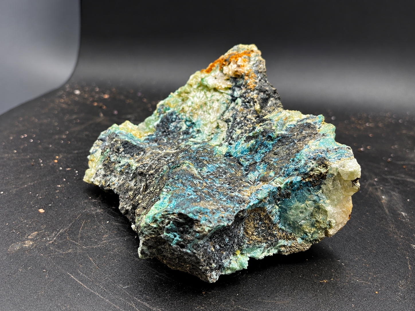 translucent selenite crystals with pale green and creamy yellow coloration growing across a dark mineral surface from Ojuela Mine
