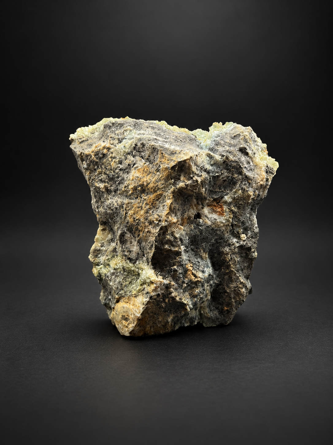 Large Mexican Blue Selenite specimen displaying blue-green mineral textures, golden crystal edges, and rugged dark matrix from a low angled perspective.