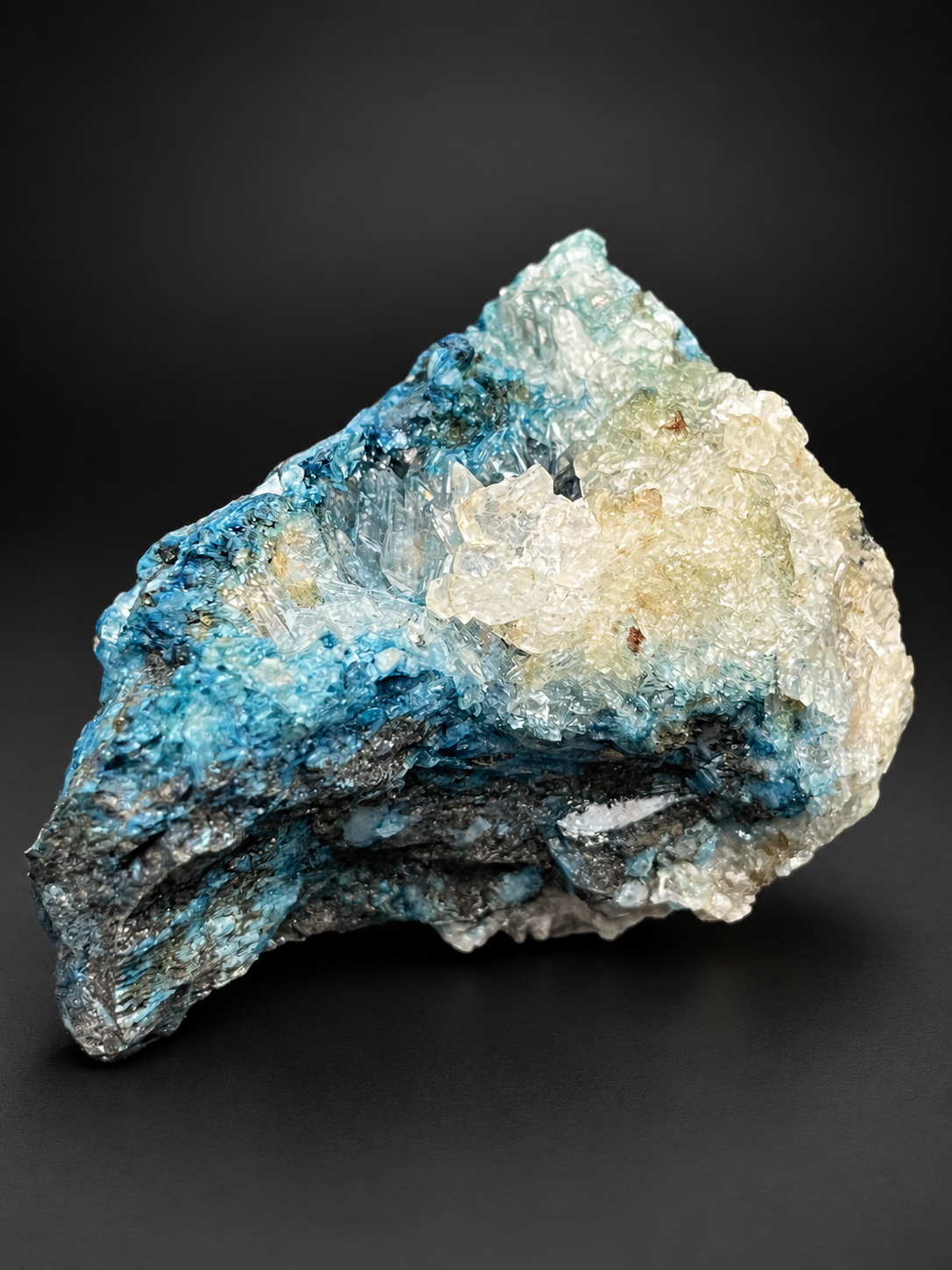 Mexican Blue Selenite specimen showing cream-colored translucent crystal formations rising above deep blue mineralization and dark textured matrix.