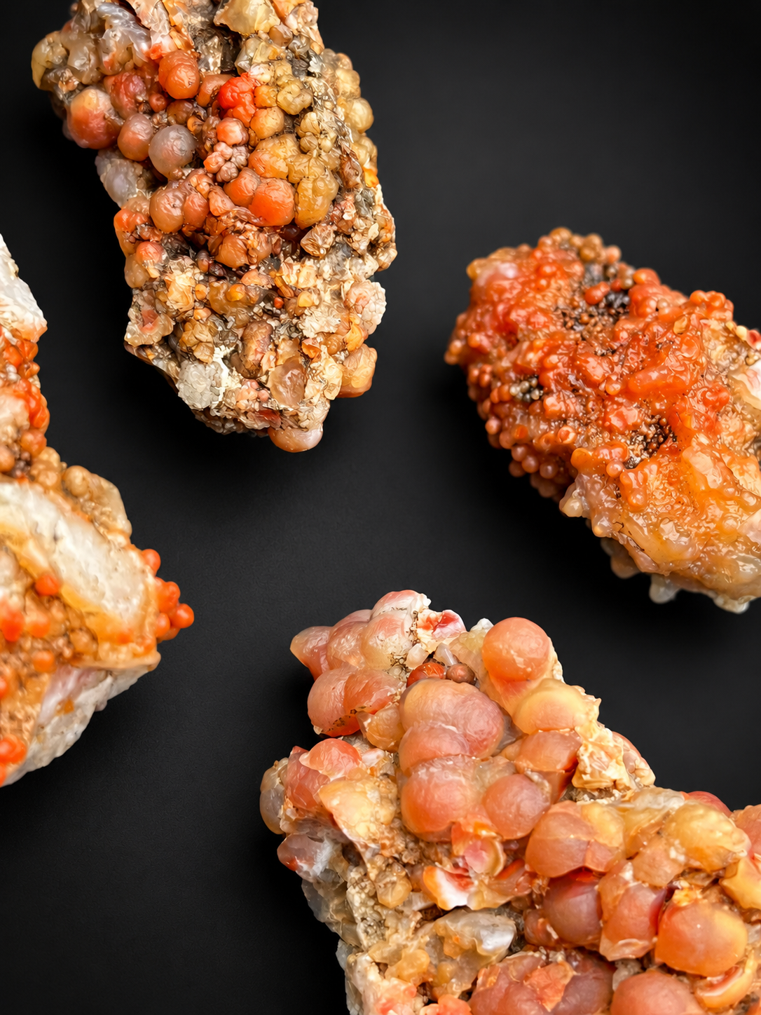 Utah Red Grape Agate specimens showing orange, peach, red, and pink botryoidal chalcedony with varying sphere sizes and textures.