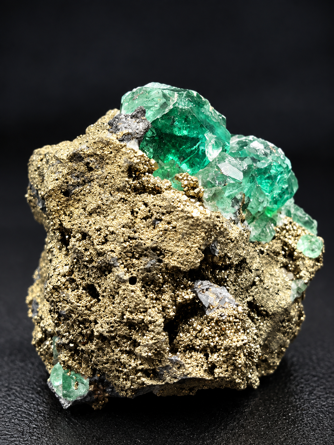 deep green translucent fluorite crystals with glassy faces beside densely crystallized golden pyrite from Atacocha Mine, Peru.