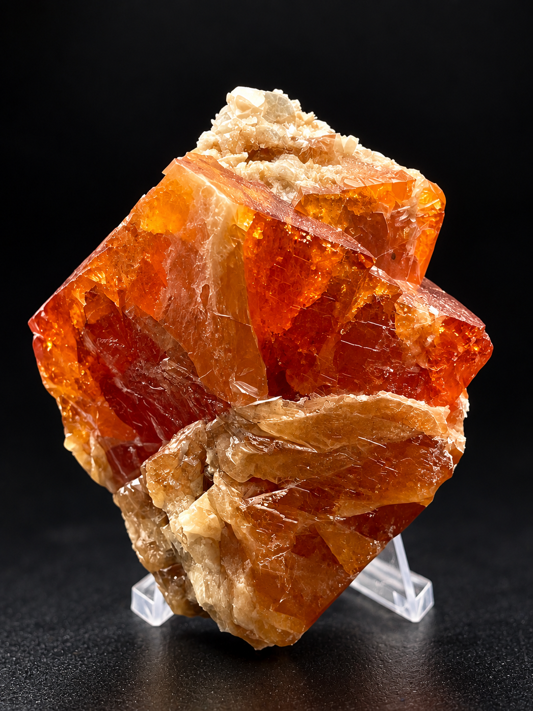 translucent reddish-orange scheelite crystals with geometric faces, golden internal reflections, and pale muscovite from Pingwu, China.