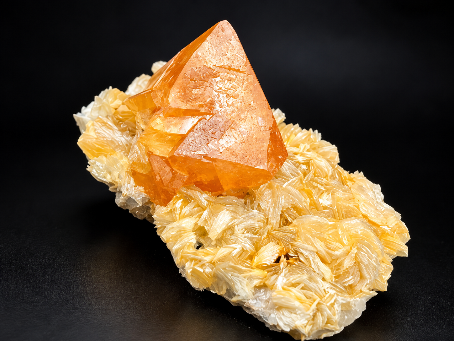 natural orange scheelite crystal rising from a low, elongated bed of delicate golden muscovite rosettes from Mt. Xuebaoding, China.