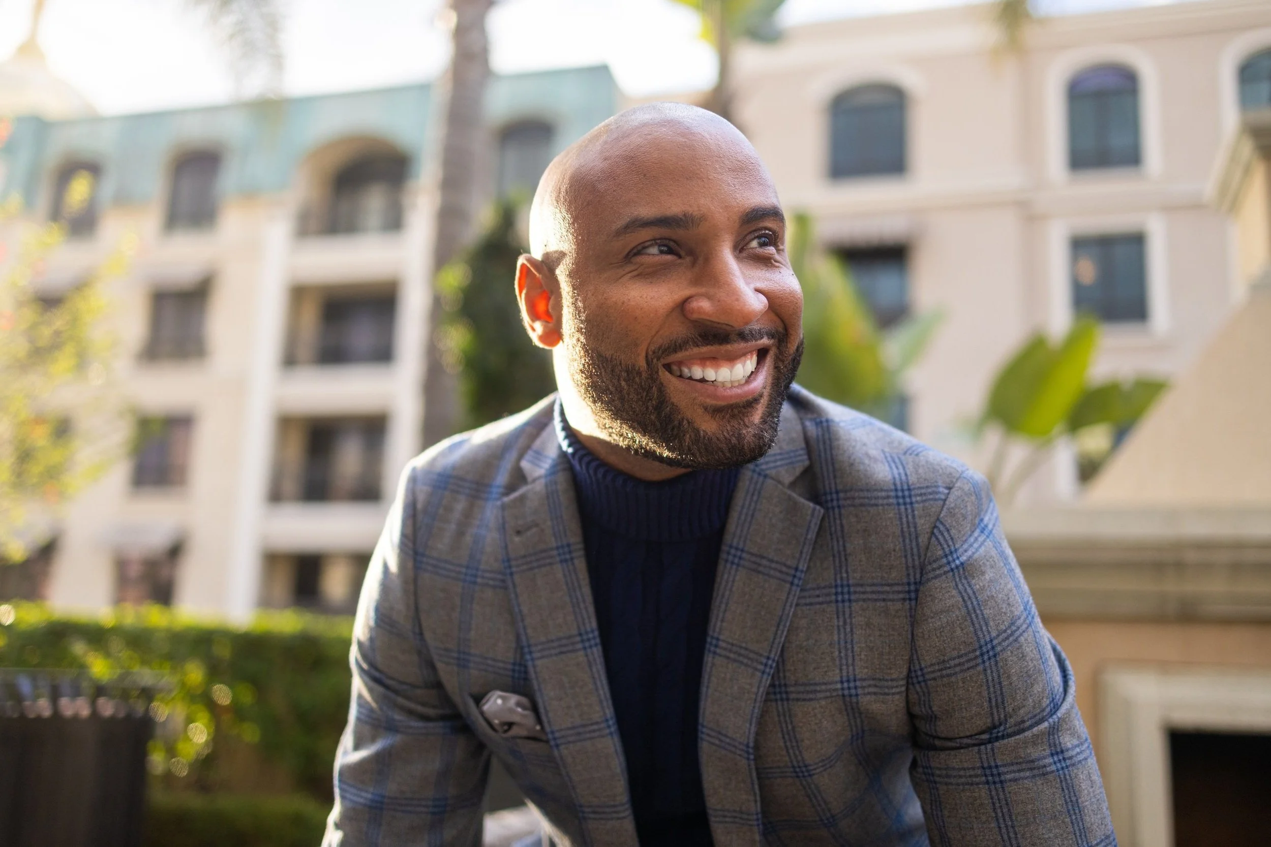 Confident client styled by San Diego wardrobe consultant John Phillip Moreno, wearing a blue plaid blazer and radiant smile.