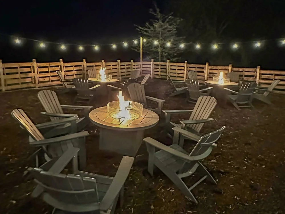 Private fire pits with Adirondack chairs under string lights