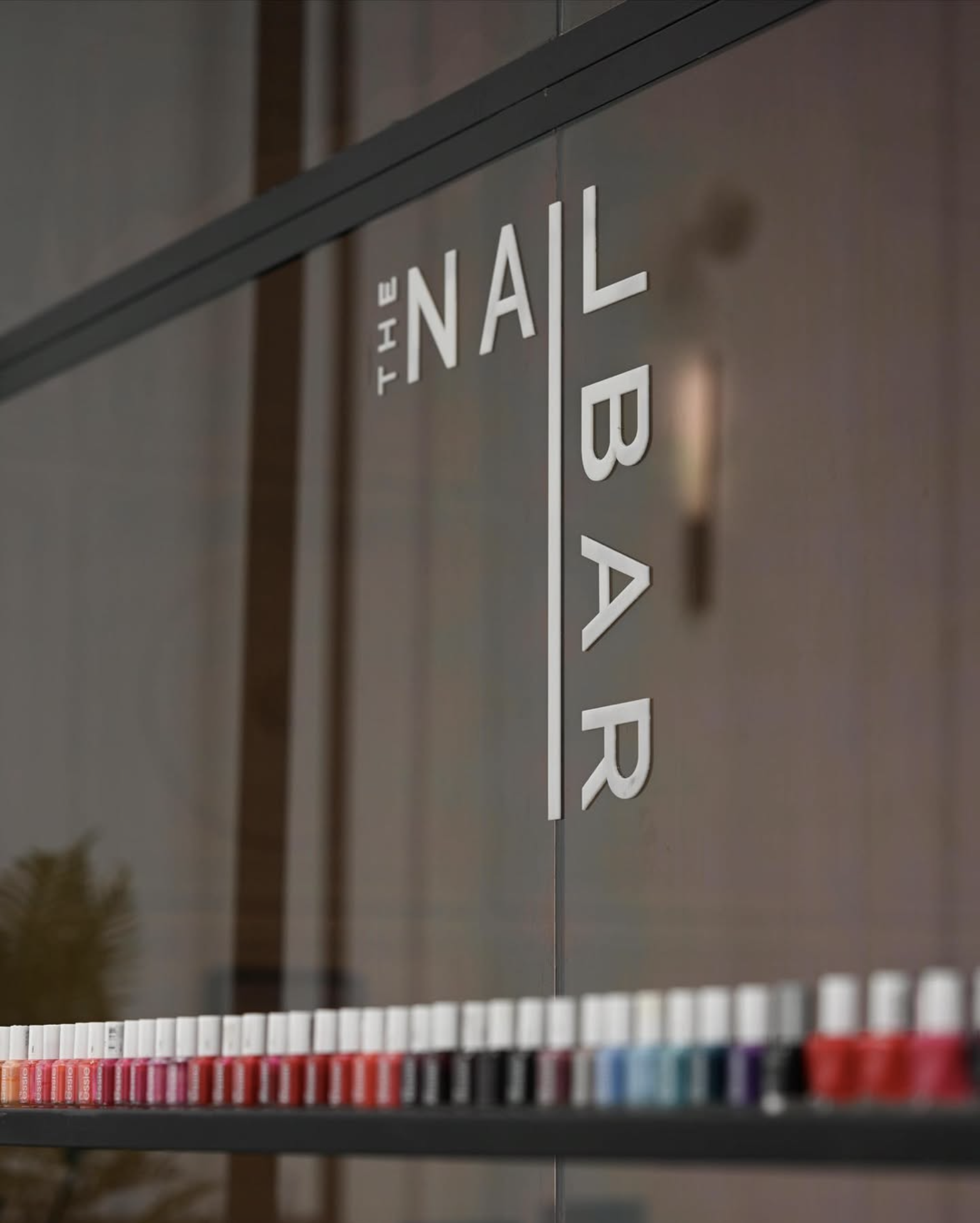 Sign reading 'The Nail Bar' with a display of colorful nail polish bottles at the bottom.