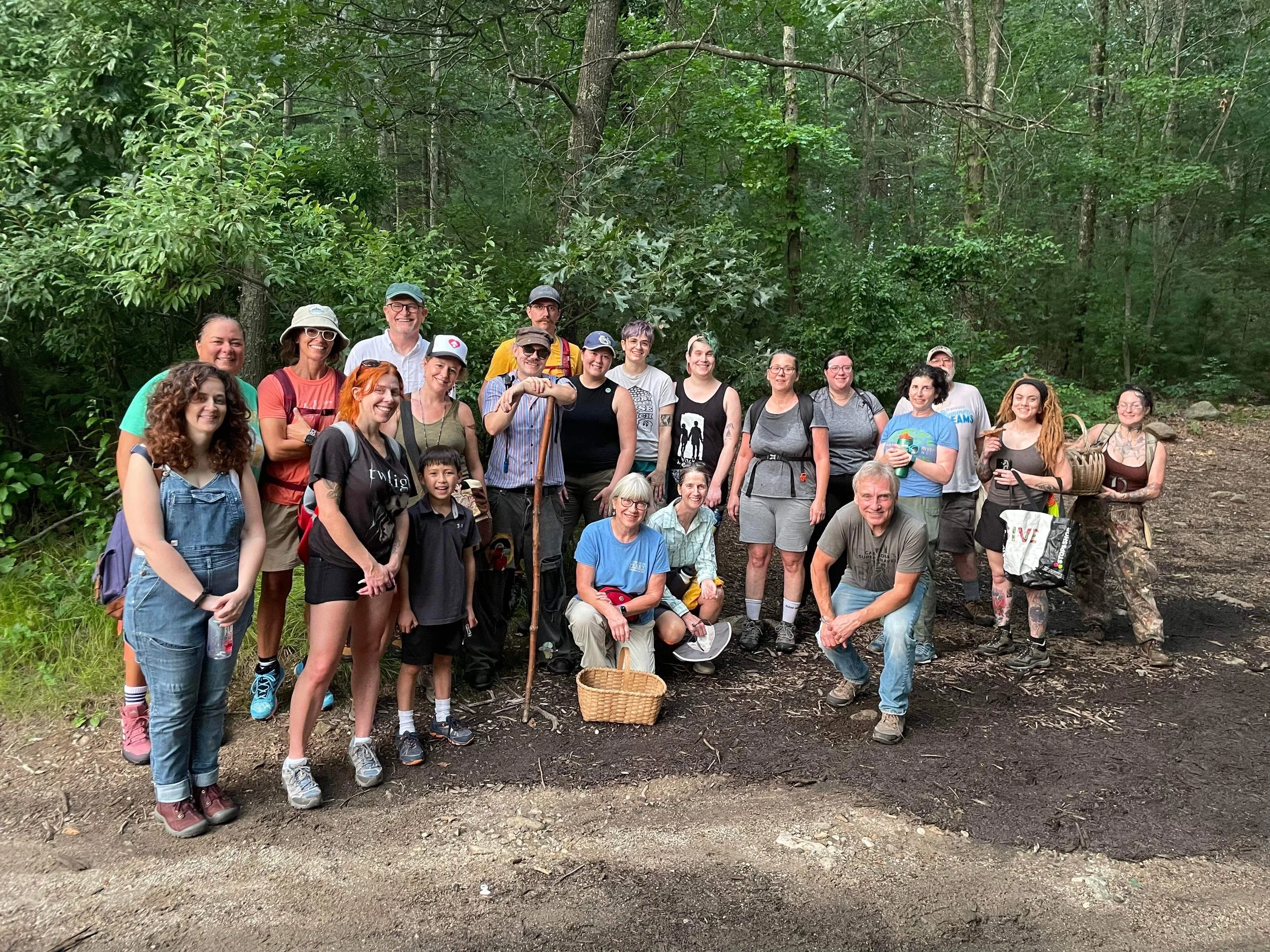 Group of people posing on a forest trail during a mushroom foray or outdoor activity.
