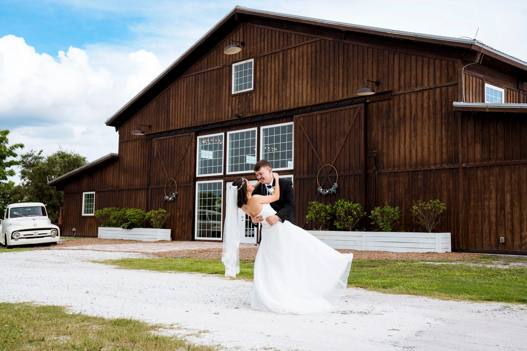 Husband dipping his newlywed wife in front of the venue barn entrance