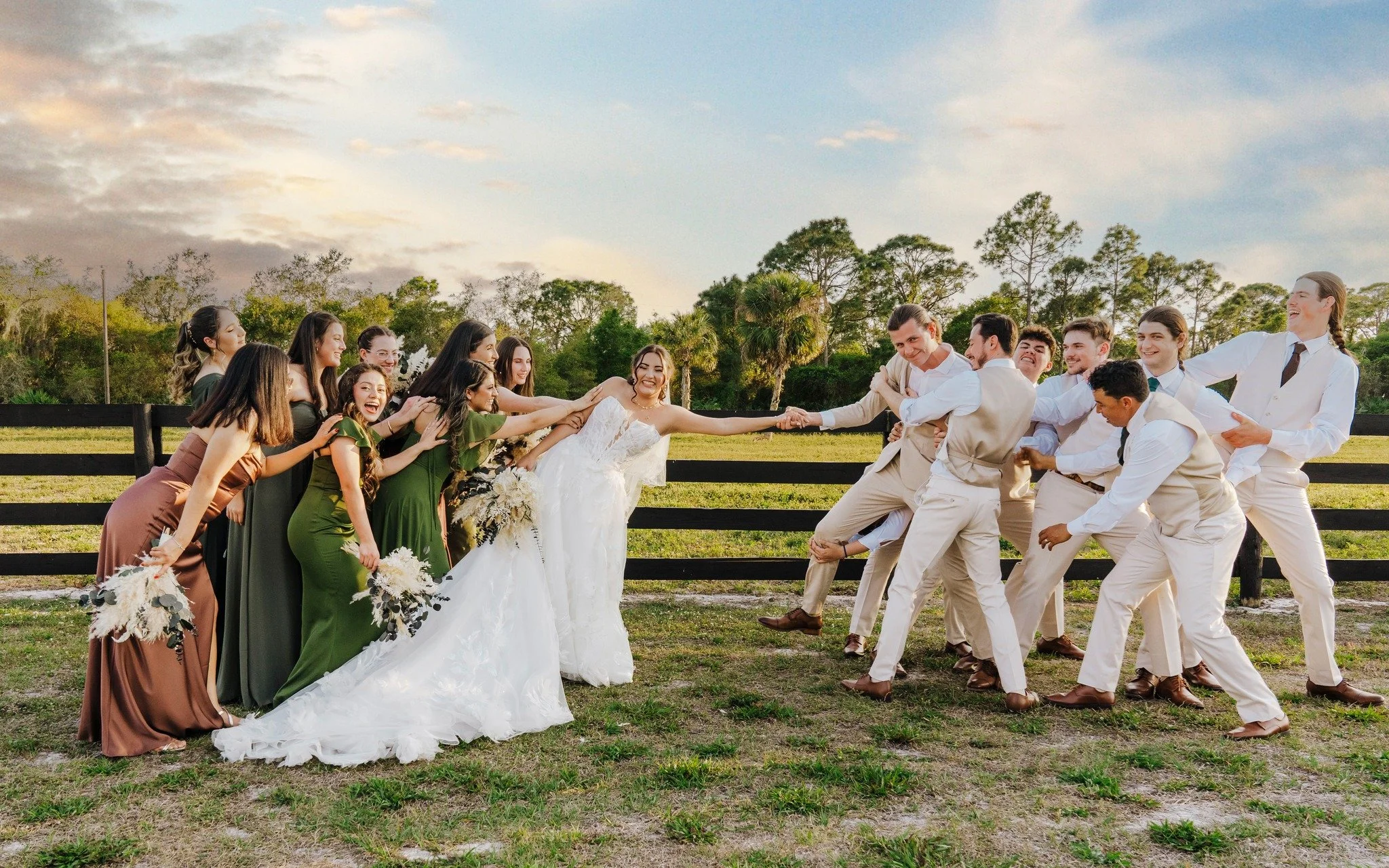 Tug of war style photo between Bride and Groom. Bridesmaids are with the bride and the groomsmen are with the groom. They are all excited for the newlywed couple.  
