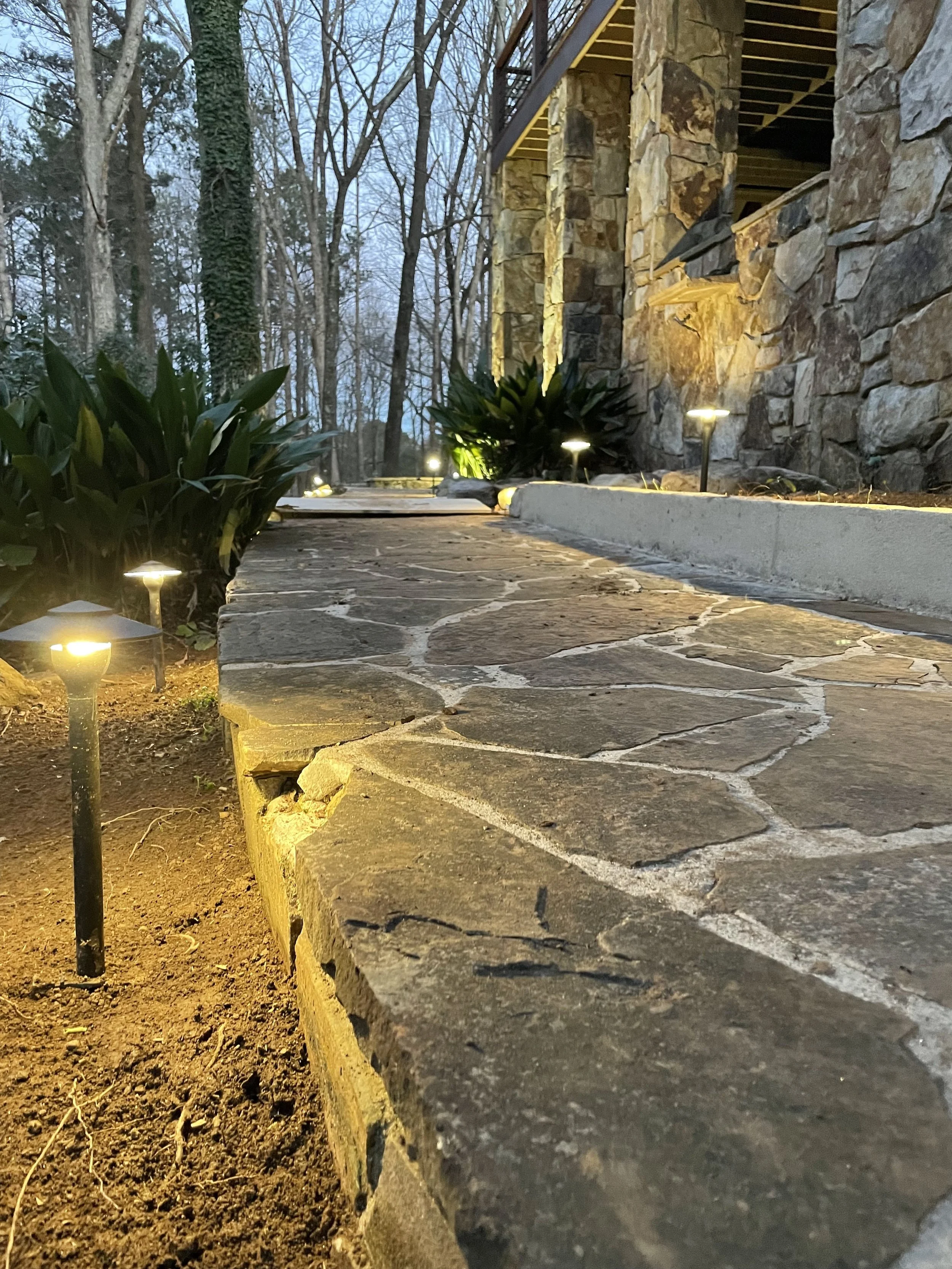 Solid cast brass low voltage LED landscape lighting fixture illuminating a stone walkway in Watkinsville GA