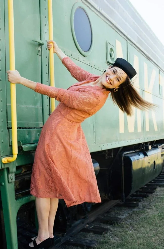 A visitor posing on the steps of the green MKT locomotive outside the Katy Depot