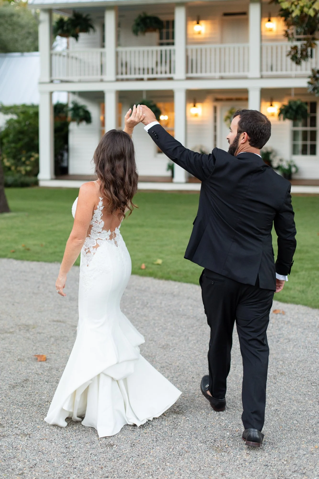 Bride being twirled by groom in front of historic southern home