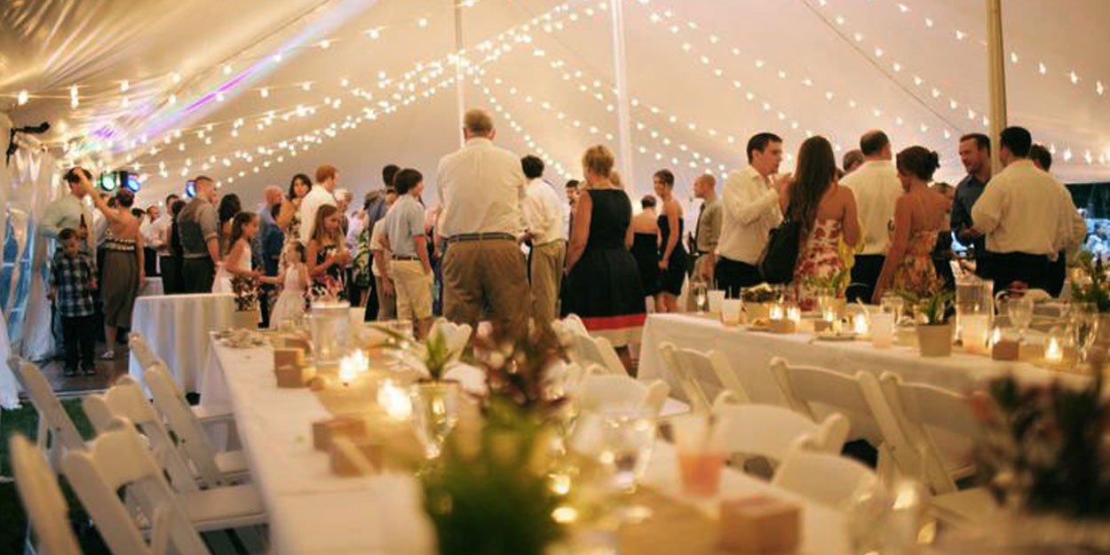  Large outdoor tents provide plenty of space for family and friends to celebrate a wedding.  