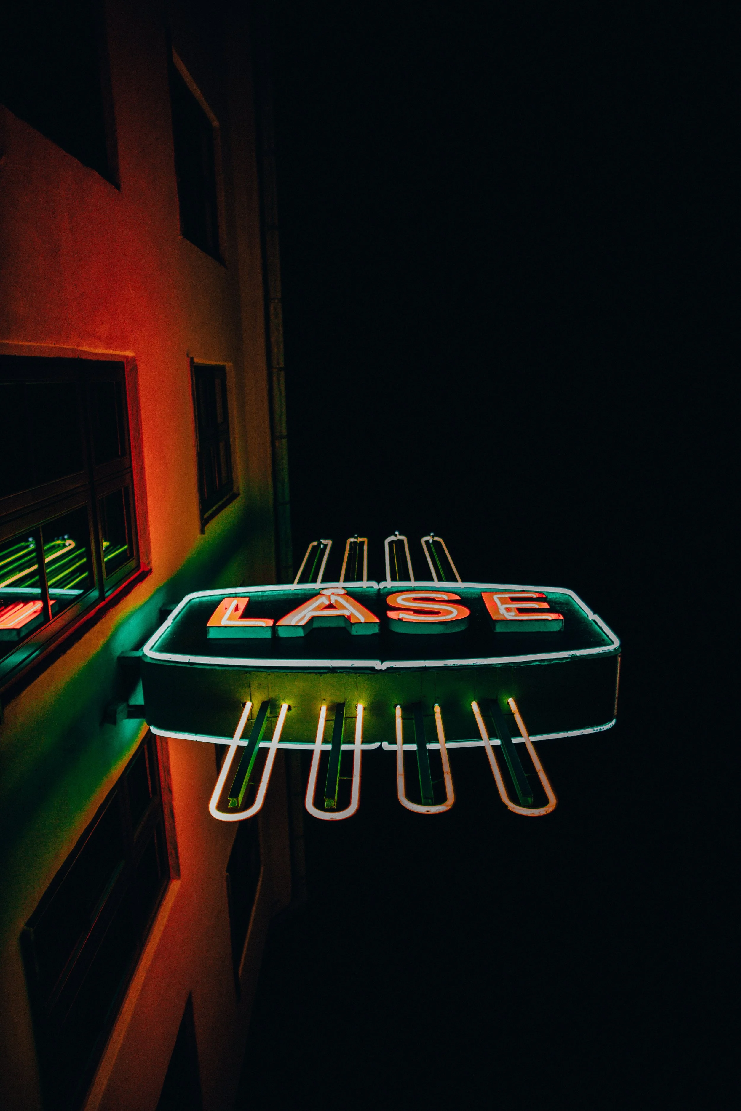 Neon sign with the word "LASE" in red across a dark night sky.