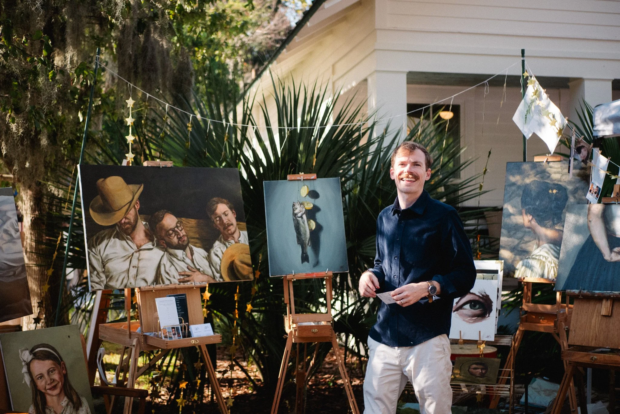 Artist painting live portrait at outdoor event with audience gathered nearby