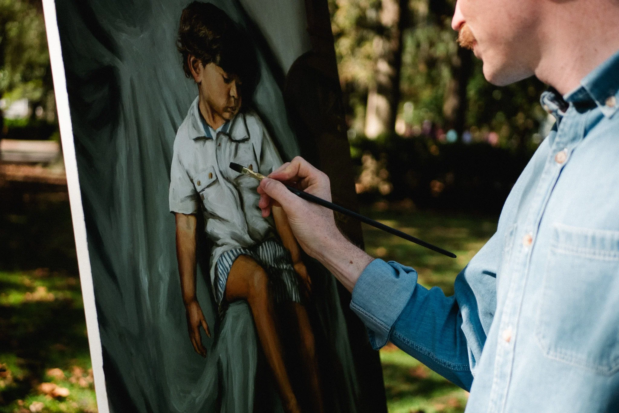 Artist painting portrait outdoors in Savannah park during live painting session